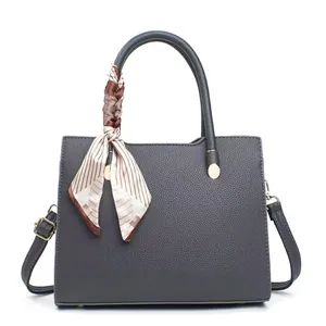 Dark grey pebble leather crossbody handbag with decorative silk scarf on white background