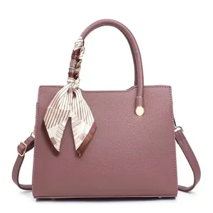 Elegant dusty pink lychee leather handbag with decorative scarf and golden hardware