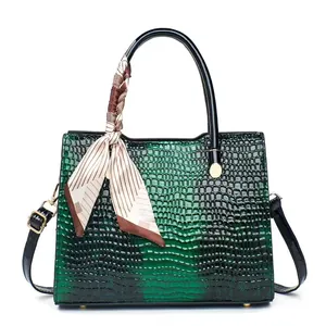 Detail of dark green crocodile texture tote with striped silk scarf and gold hardware