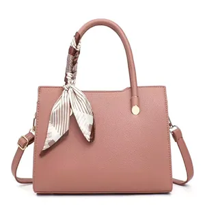 Detail of dusty pink pebbled leather handbag with silk scarf wrap and golden rivets
