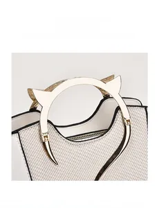 Dettaglio borsa a conchiglia in tweed con bordi in pelle e manici dorati a forma di gatto