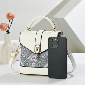 White pixel-style handbag with geometric pattern, gold bear buckle, and shoulder strap