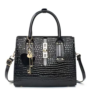 Sac à main noir brillant motif crocodile avec détails dorés et pendentif cœur chic