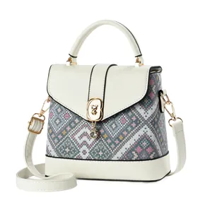 Crossbody bag with pixel geometric pattern and bear pendant on a white background