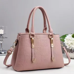 Detail of light pink pebbled leather handbag featuring gold metallic buckles and straps