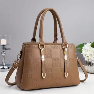 Brown handbag with geometric embossed pattern and adjustable shoulder strap on gray background