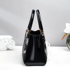 Détail du sac à main noir aspect serpent avec ferrures dorées et pendentif en perle