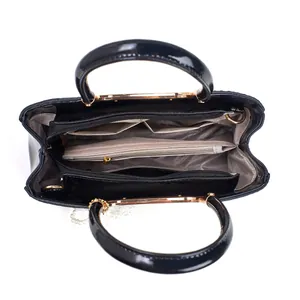 Vue intérieure du sac à main en cuir verni noir avec compartiments et détails dorés brillants