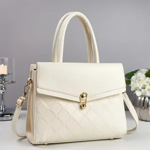 Detail of cream crossbody bag featuring lychee texture and gold metal twist lock