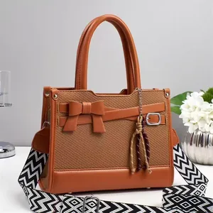Borsa a mano intrecciata marrone con fiocco in pelle e tracolla a motivi geometrici