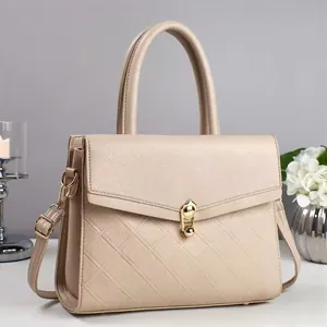 Detail of beige lychee leather handbag featuring gold metal clasp and diamond lattice pattern