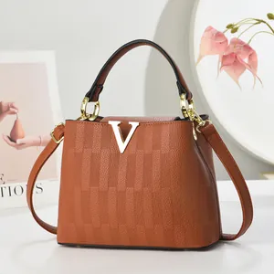 Détail du sac bandoulière marron caramel en cuir texturé avec logo en V doré métallique