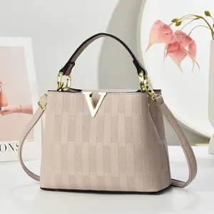 Détail d'un sac à main en cuir rose avec boucle métallique en V dorée et poignée ronde