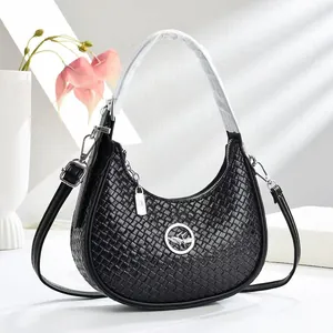 Détail du sac croissant tissé noir avec logo en métal rond et fermeture zippée