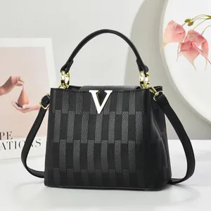 Sac à main élégant en cuir noir avec texture verticale et emblème V doré sur le devant