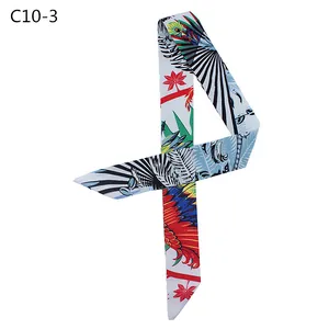 Detalle de plumas de aves tropicales en un pañuelo largo de seda con extremos en diagonal