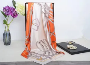 Close-up of a large orange and white silk scarf with luxury chain and belt print detail