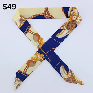 Detail of slim retro chain print twilly scarf with elegant gold fringe on navy blue silk