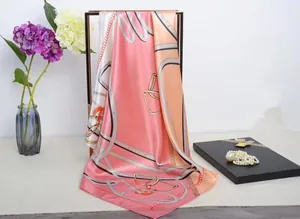 Detail of silk square scarf with horse bridle patterns and chains hanging on metal frame