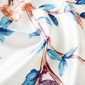Detailaufnahme von seidigem Stoff mit blauen Blättern und orangeroten Blumen
