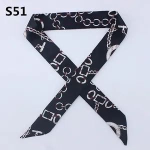 Detail of a black skinny scarf featuring golden chain patterns and silky satin texture