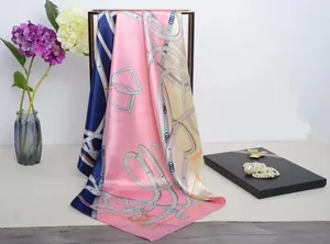 Detail of silk scarf with chain and belt patterns displayed on a gold rack with flowers