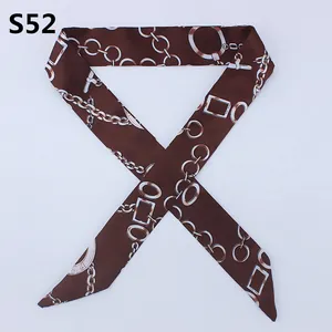 Detailed close-up of brown skinny silk scarf with golden chain patterns for bag handles