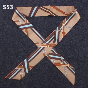 Close-up of narrow silk twilly scarf with equestrian buckle patterns and diagonal ends