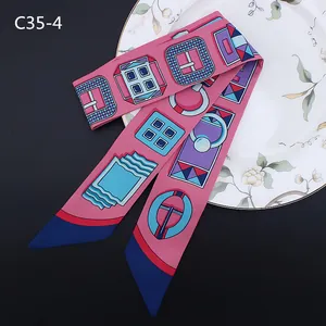 Détail macro du foulard twilly en satin rose avec motifs géométriques sur assiette fleurie
