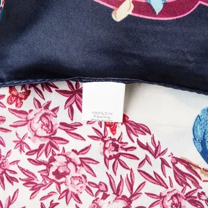 Makroaufnahme des 90cm Seidengefühl-Schals mit Blumenmuster und Materialetikett aus Polyester