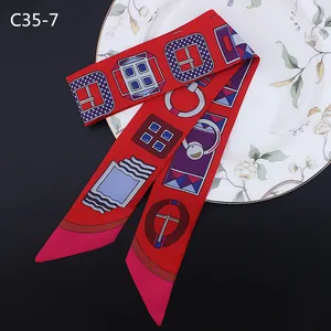 Détail d'un foulard en soie rouge avec motifs de boucles sur un plateau céramique