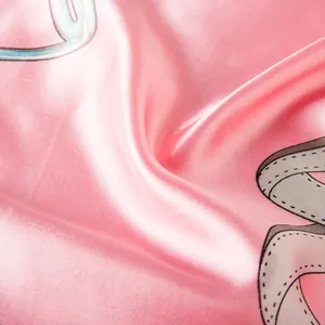 Macro detail of glossy pink satin scarf featuring premium chain and belt pattern prints