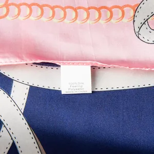 Detail view of the washing label on a silk-feeling polyester scarf with chain patterns