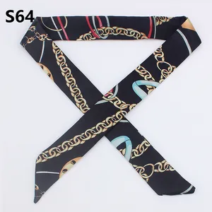 Flat lay of a black skinny silk scarf with golden chain pattern and pointed ends