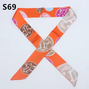 Macro view of orange silk twilly scarf with decorative horse carriage and logo emblems