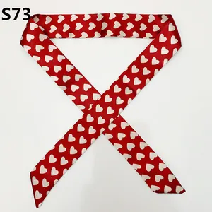 Detail of red satin bag scarf with white heart patterns and elegant pointed ends