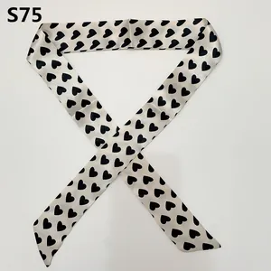 Close-up of cream skinny silk scarf with black heart pattern for handbag handle wrap