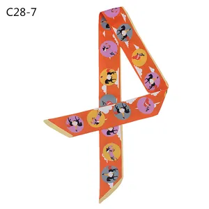 Macro detail of silk-like twilly scarf with orange circus prints for handbag handles