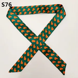 Detail view of dark green satin scarf with orange heart patterns and diagonal cut ends
