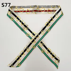 Close-up of a satin twilly scarf with green and red stripes and gold metal buckle pattern