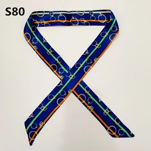 Macro view of blue Twilly silk scarf with gold chain patterns and sleek fabric texture