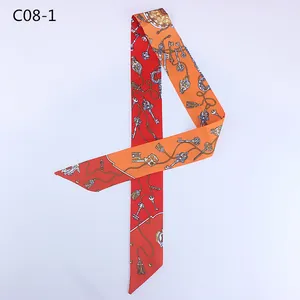 Detailed close-up of a red and orange silk twilly scarf with vintage key and chain patterns