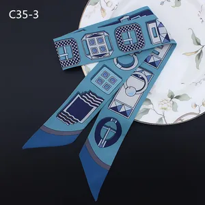Foulard twilly étroit en soie aux motifs géométriques bleus élégamment posé sur plat