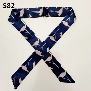 Close-up of pink flamingo print on dark blue twilly scarf with smooth satin texture