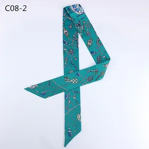 Detail of teal twilly scarf with golden key and blue tassel print on white background
