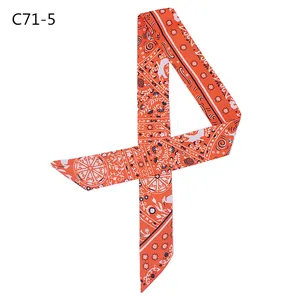 Close-up of bohemian silk-like twilly scarf with orange ethnic patterns and pointed ends