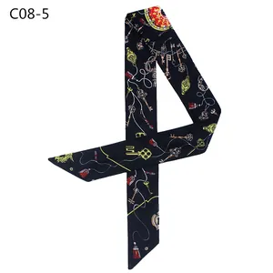 Close-up of black satin twilly scarf featuring vintage key and red tassel print details