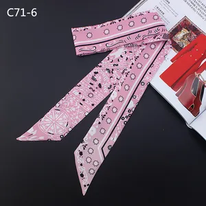 Detail of a pink silk-feel Twilly scarf with floral prints on a dark background