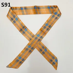 Close-up of orange satin ribbon scarf with classic plaid pattern tied in an X-shape