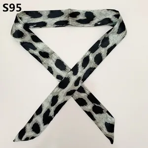 Macro detail of slim leopard print scarf tied on handbag handle with pointed ends